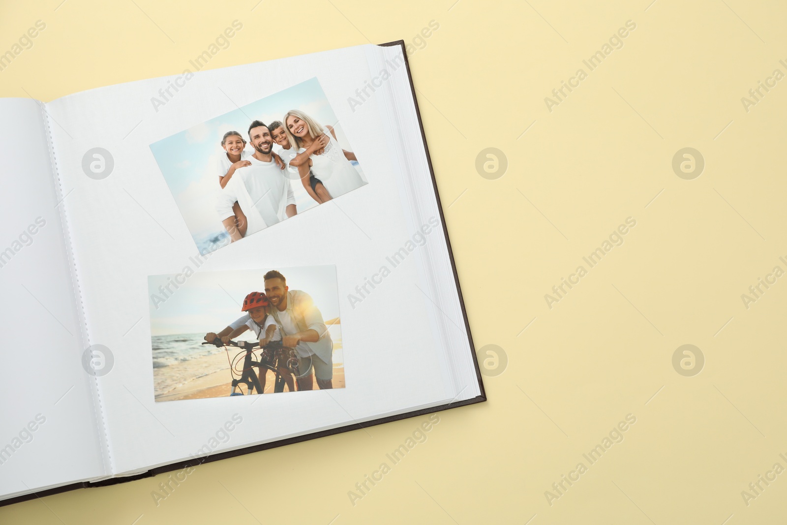 Photo of Open photo album with photos on beige background, top view. Space for text