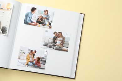 Photo of Open photo album with different photos on beige background, top view