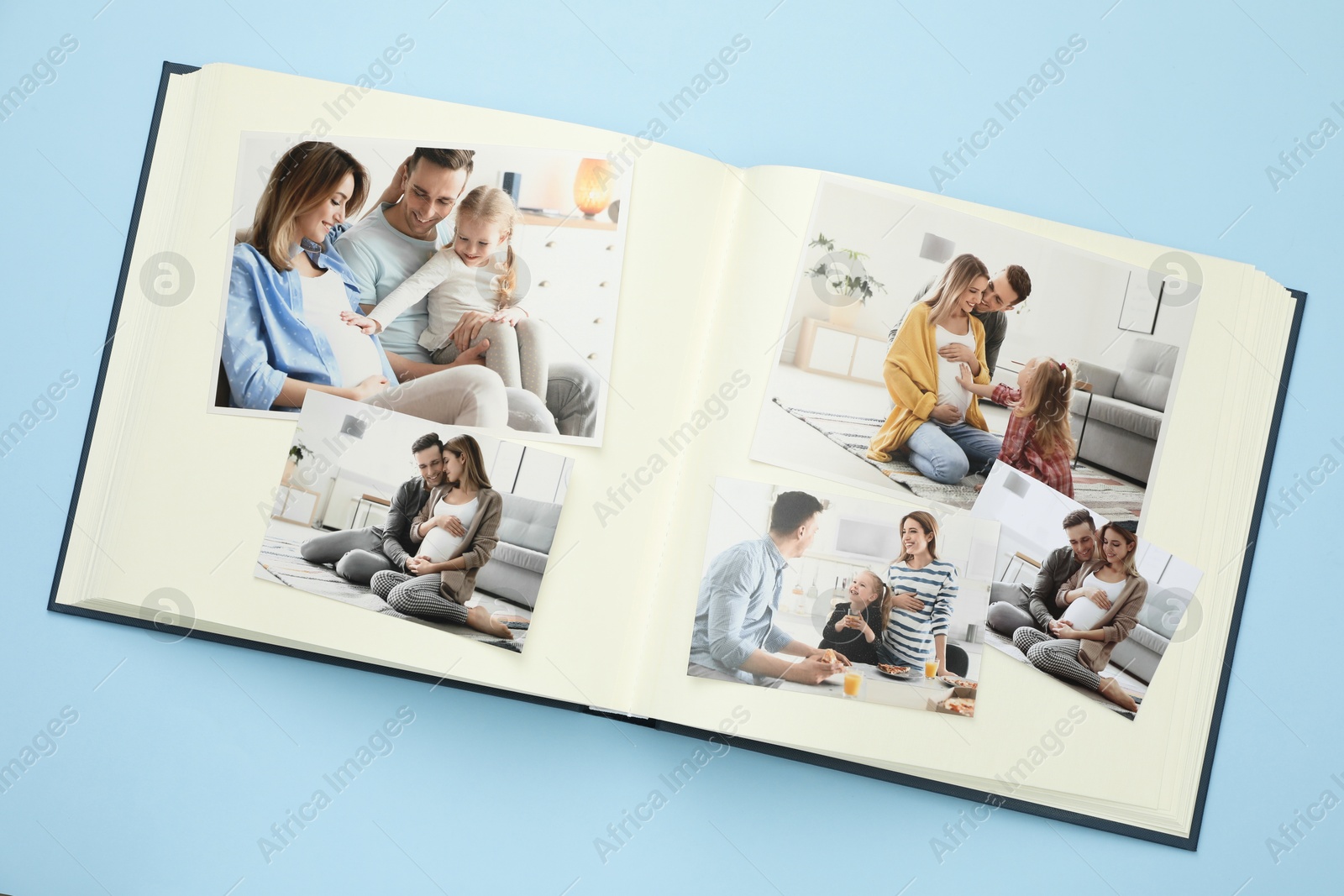 Photo of Open photo album with different photos on light blue background, top view