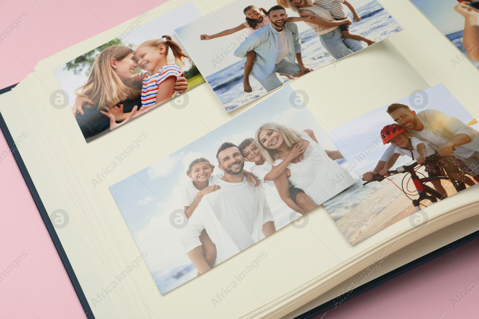 Photo of Open photo album with different photos on pink background, closeup