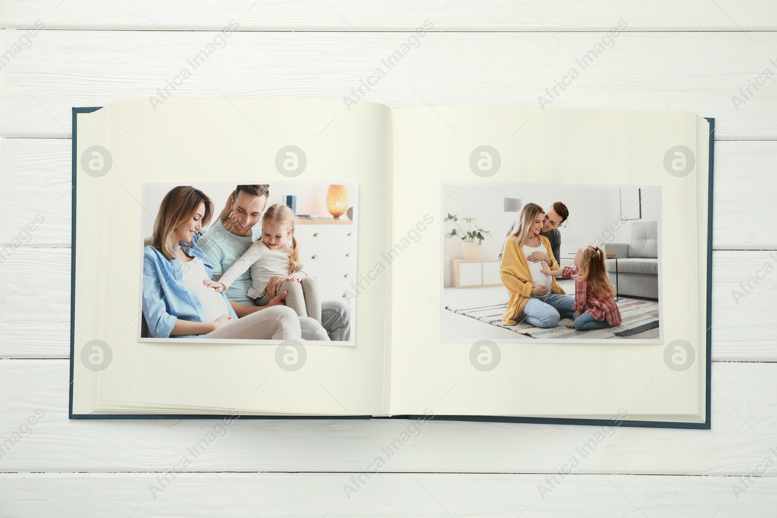 Photo of Different photos in open photo album on white wooden table, top view