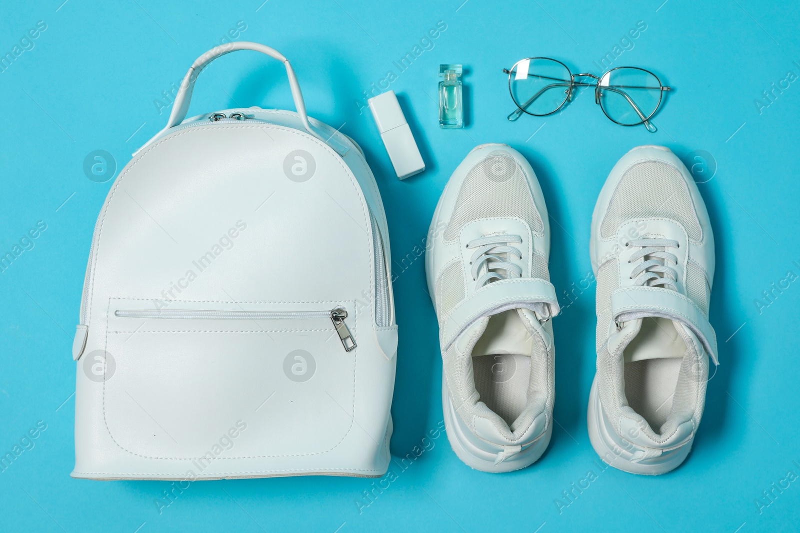 Photo of Stylish sneakers and accessories on light blue background, flat lay