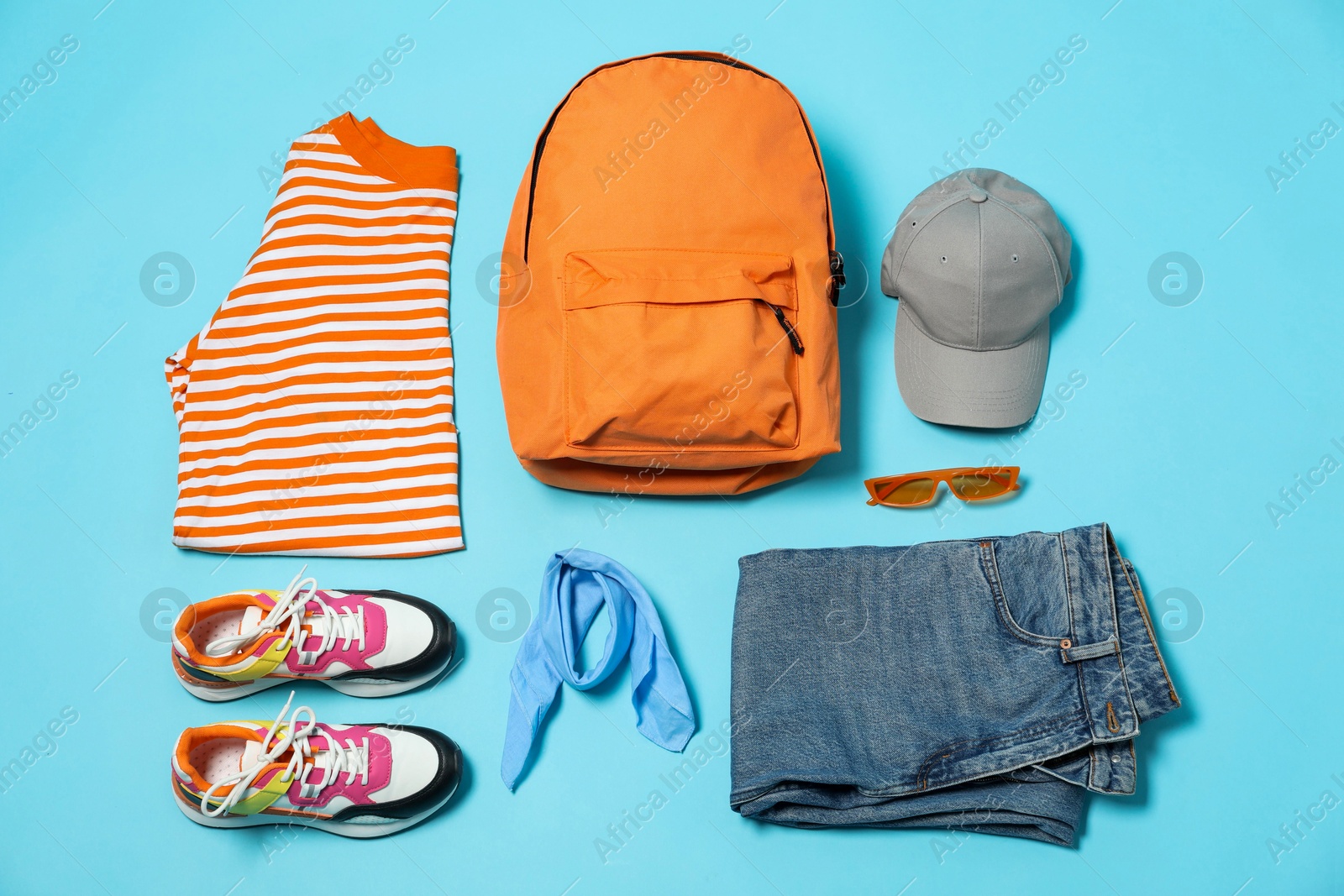 Photo of Stylish outfit with backpack on light blue background, flat lay