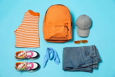 Photo of Stylish outfit with backpack on light blue background, flat lay