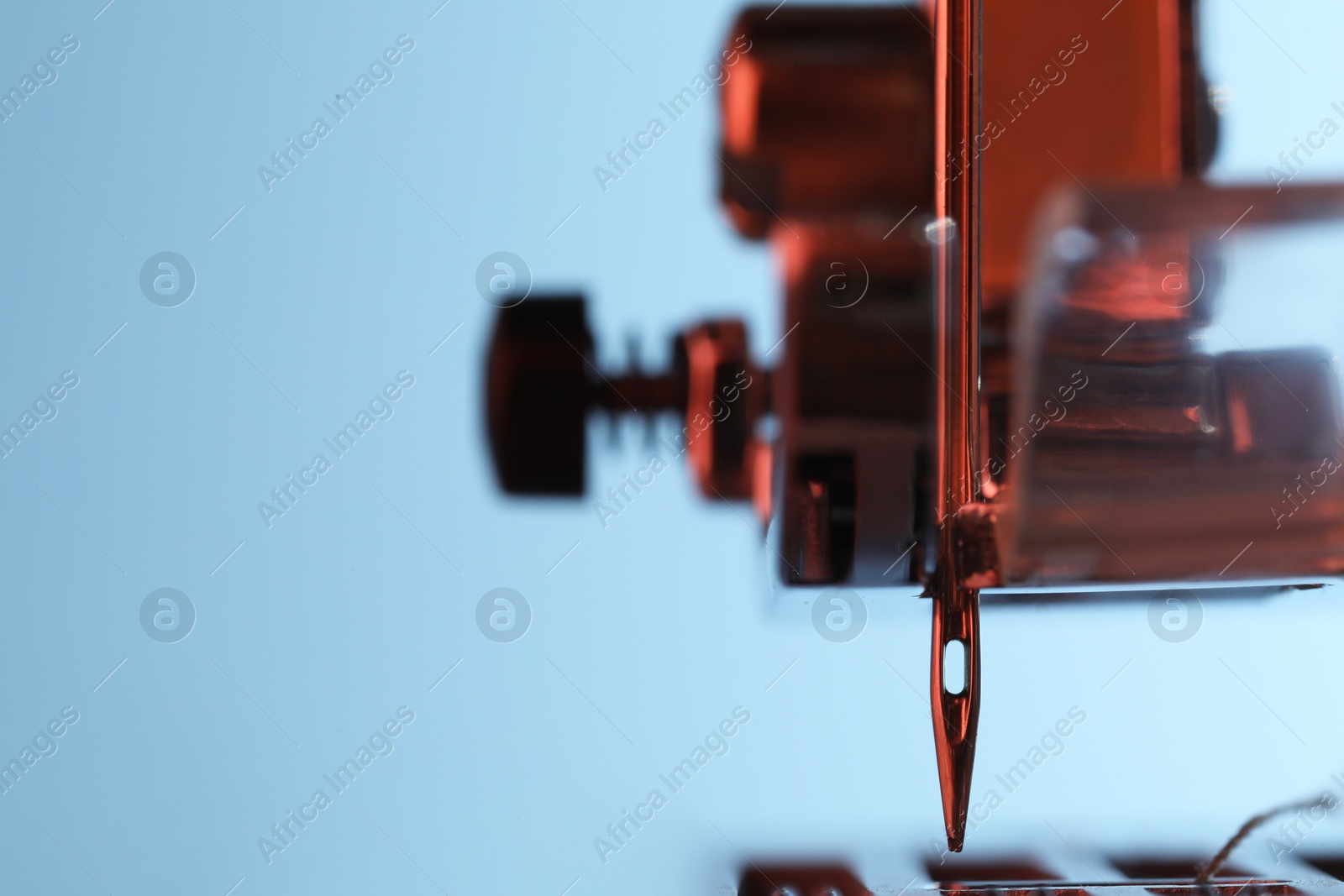 Photo of Sewing machine on light blue background, macro view. Space for text