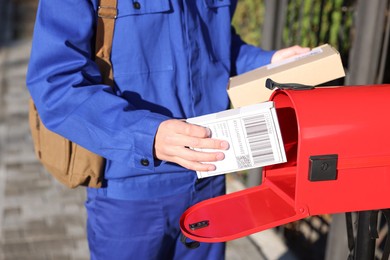 Photo of Postman putting parcel into mail box outdoors, closeup