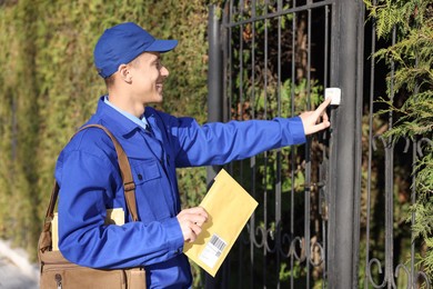 Photo of Postman with parcel ringing entrance bell outdoors