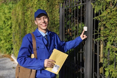 Photo of Postman with parcel ringing entrance bell outdoors