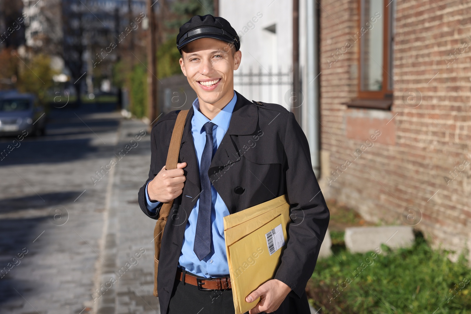 Photo of Happy postman with parcels outdoors. Mail service