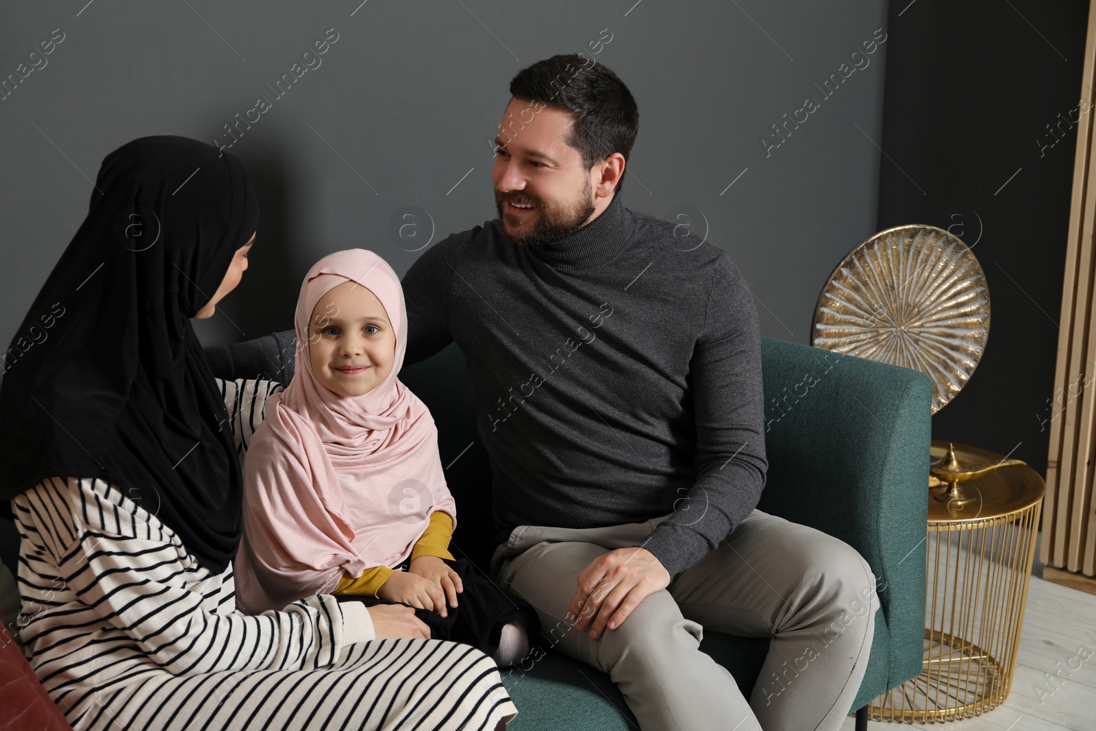 Photo of Happy Muslim family sitting on sofa at home