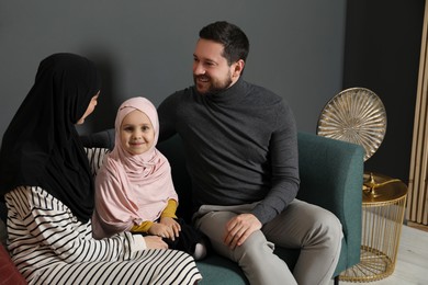 Photo of Happy Muslim family sitting on sofa at home