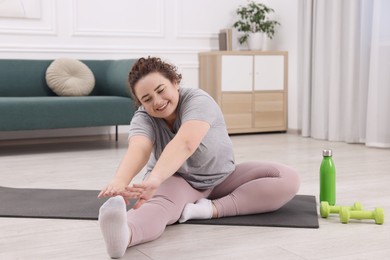 Photo of Plus size woman stretching during fitness training at home