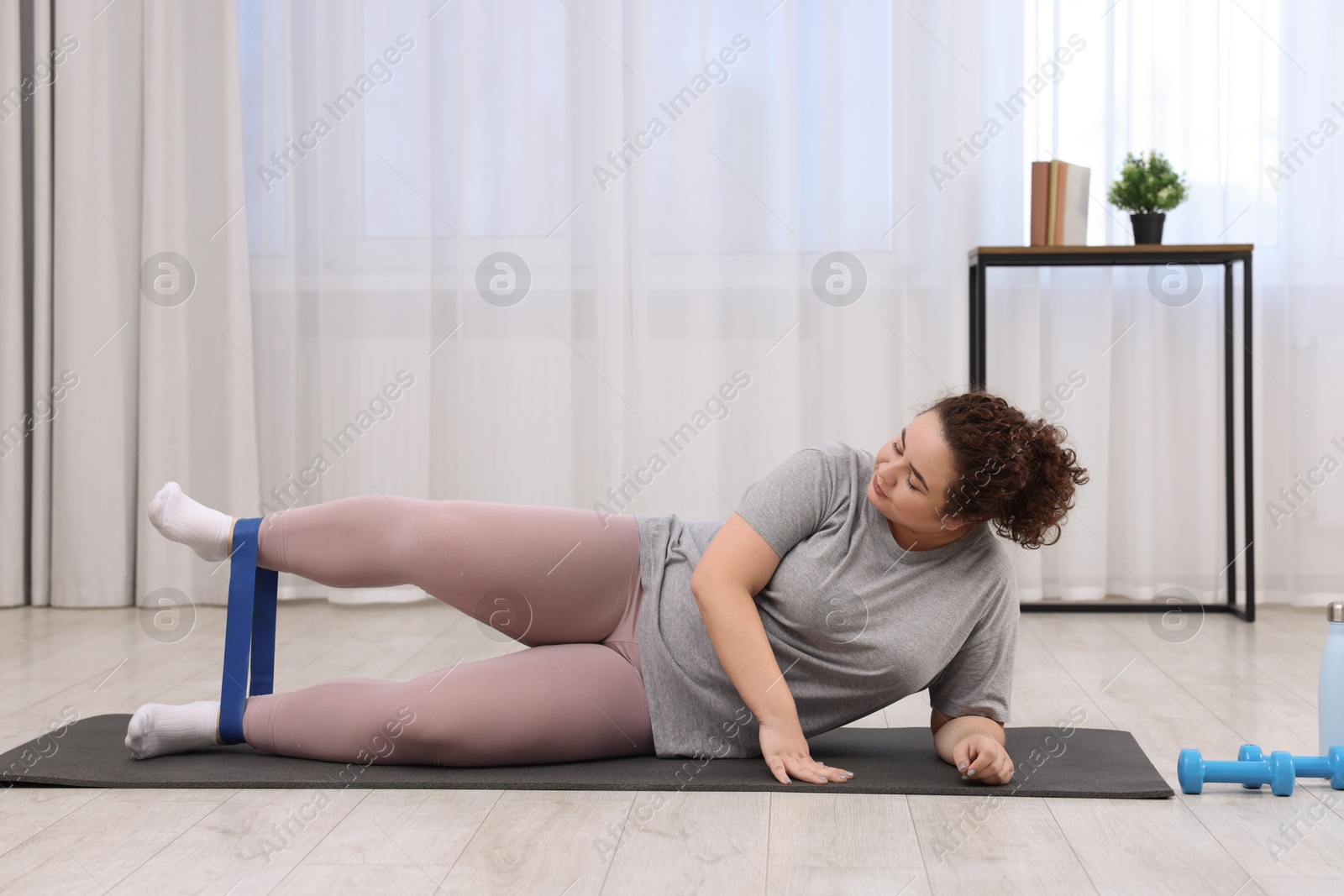 Photo of Woman training with resistance band at home