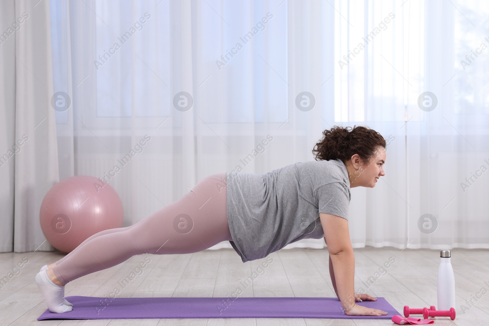 Photo of Woman doing plank exercise on fitness mat at home