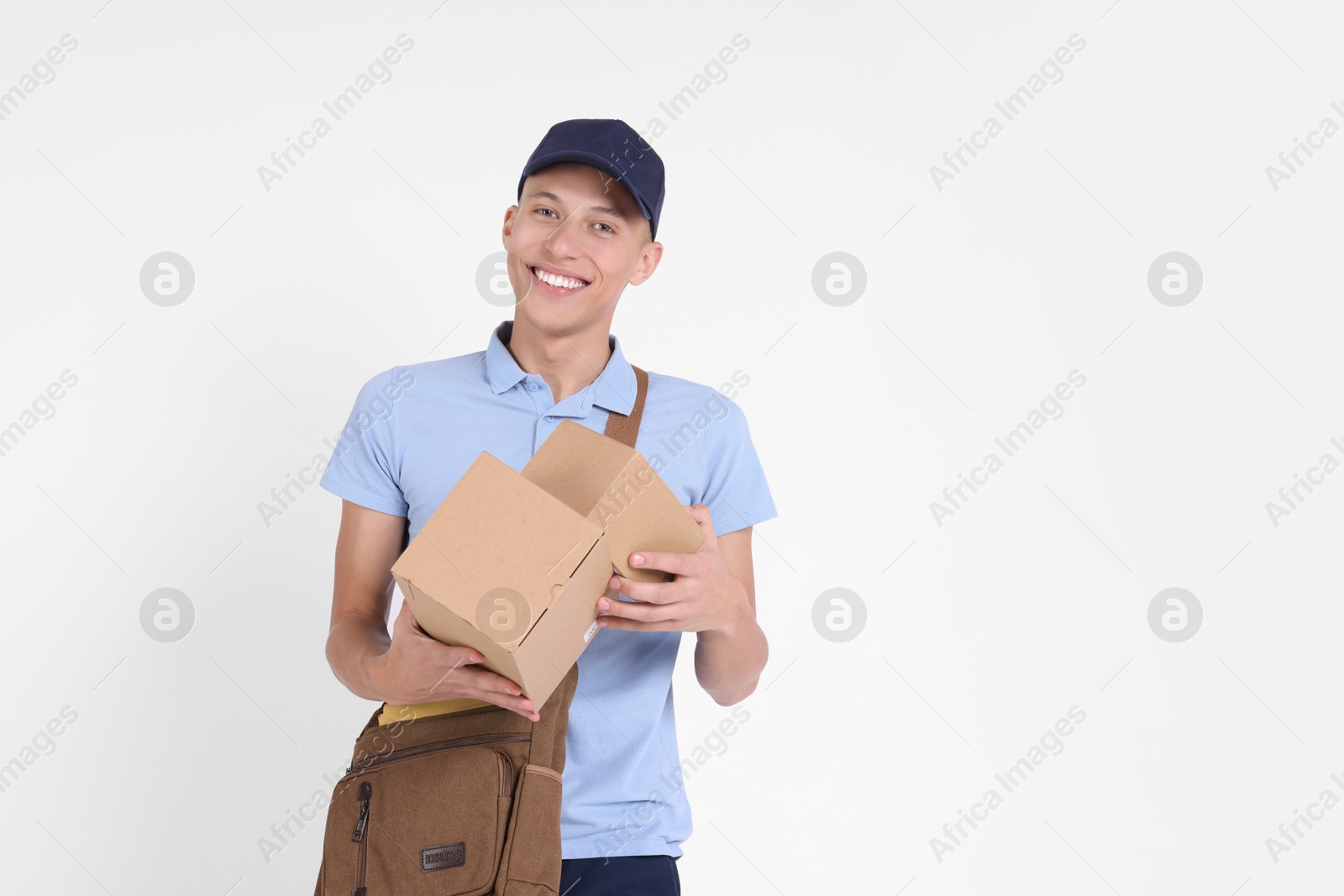 Photo of Happy postman with bag and parcels on white background