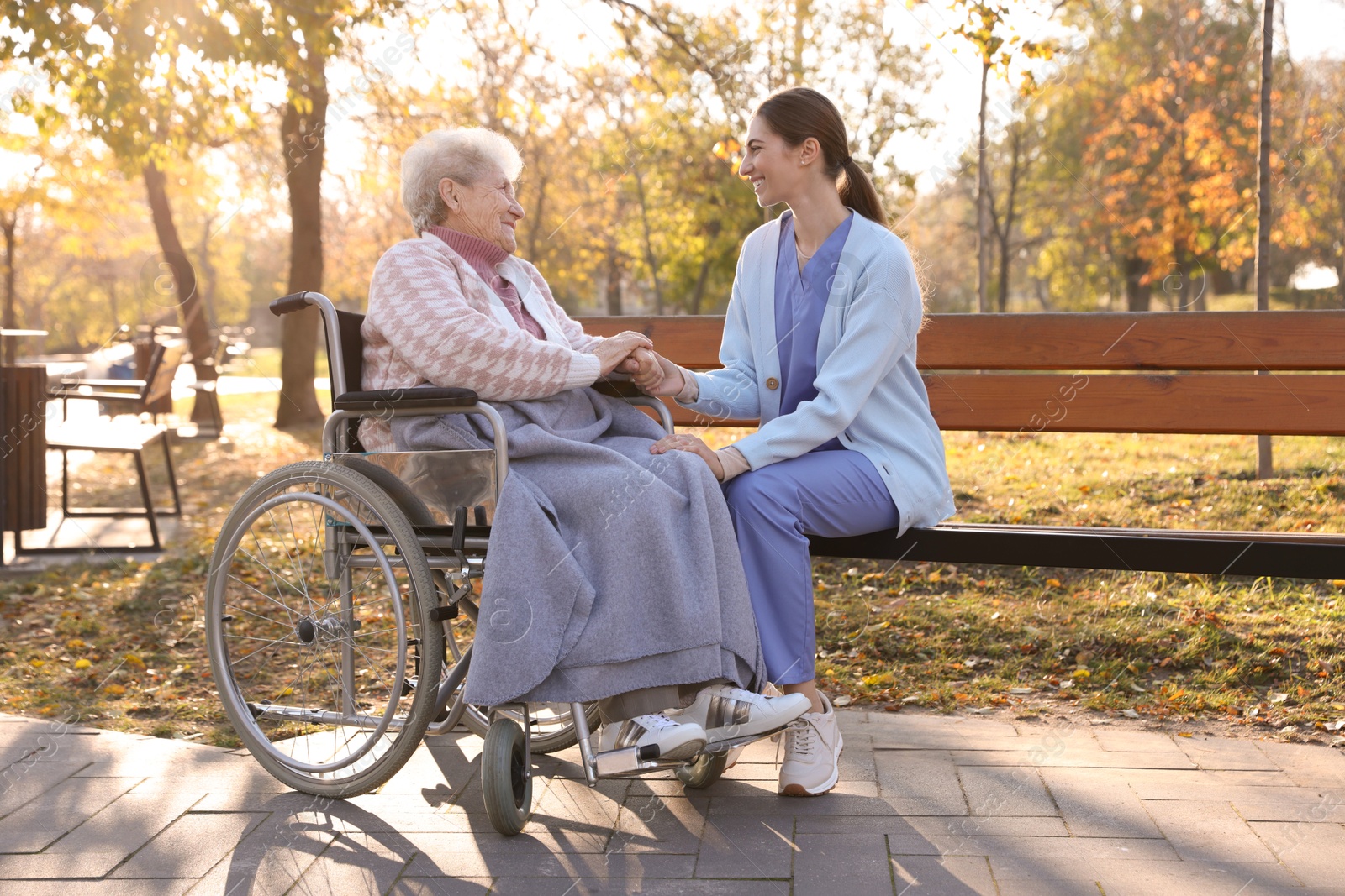 Photo of Caregiver with elderly woman in wheelchair at park