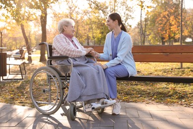 Photo of Caregiver with elderly woman in wheelchair at park