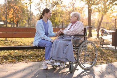 Photo of Caregiver with elderly woman in wheelchair at park