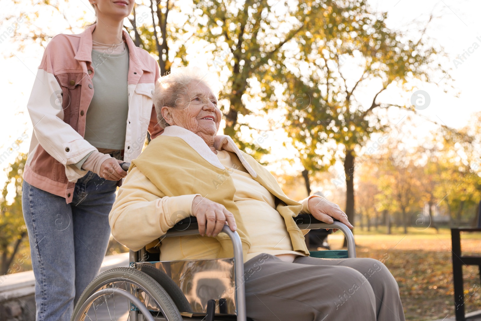 Photo of Caregiver with elderly woman in wheelchair at park