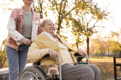 Photo of Caregiver with elderly woman in wheelchair at park