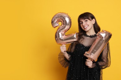 Photo of Coming of age party - 21st birthday. Young woman holding number shaped balloons on yellow background, space for text