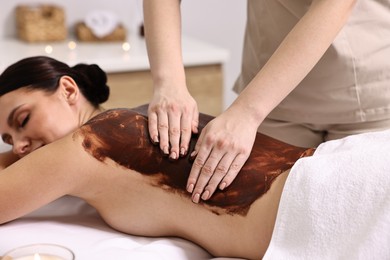 Photo of Woman undergoing chocolate body wrap treatment in spa salon