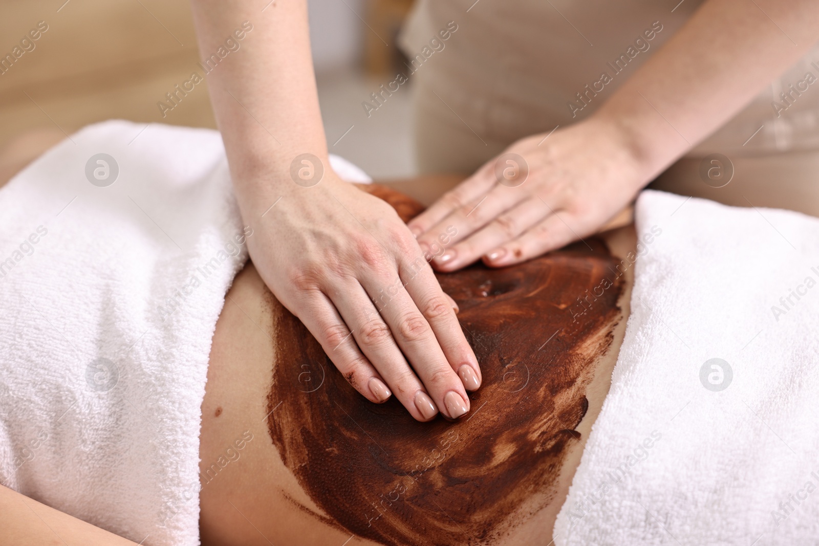 Photo of Woman undergoing chocolate body wrap treatment in spa salon, closeup