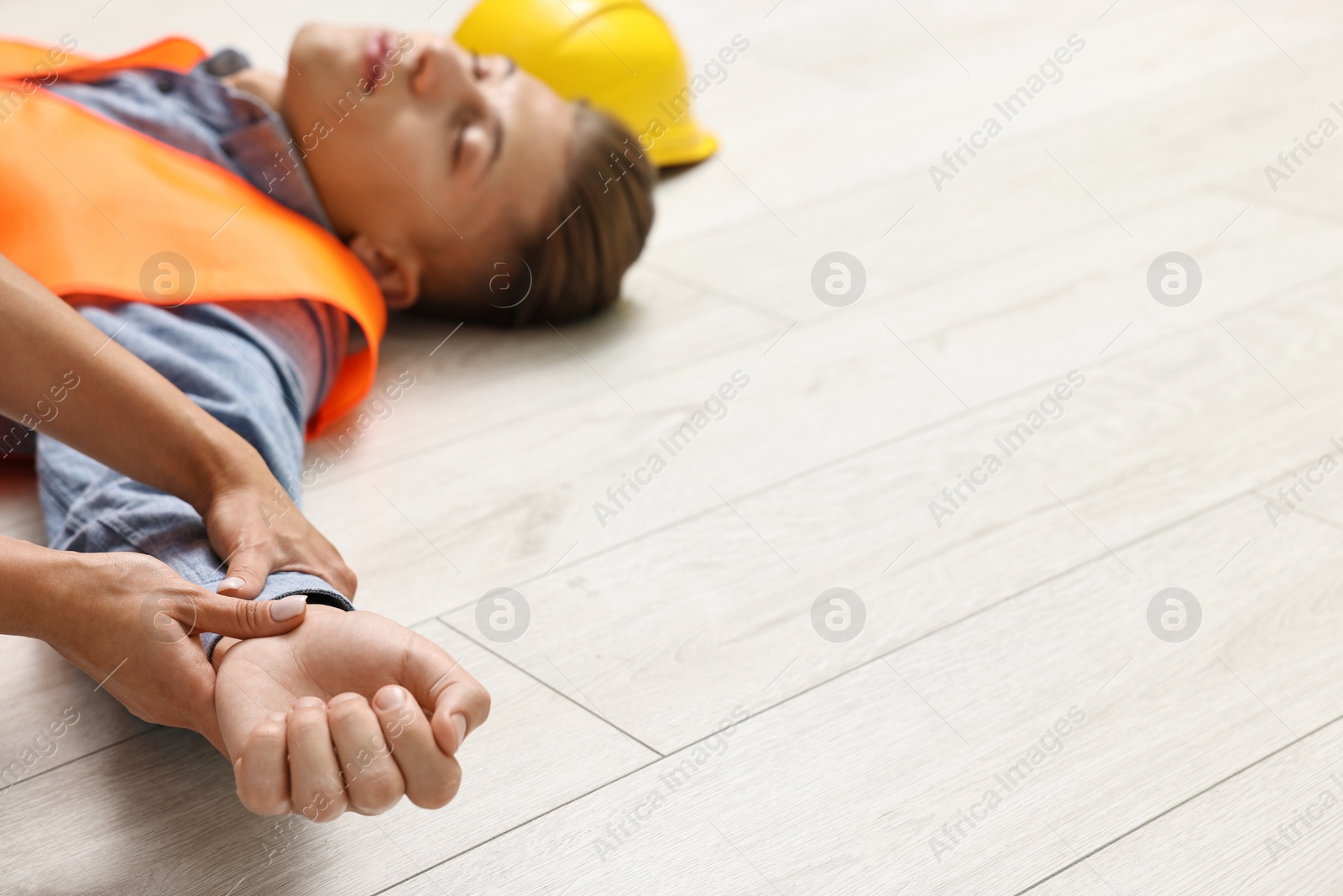 Photo of First aid. Woman checking pulse of her unconscious colleague indoors, closeup. Space for text