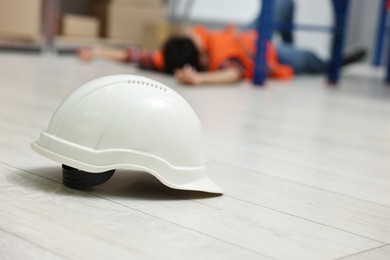 Photo of Accident at work. Hardhat on floor and unconscious woman in warehouse, selective focus