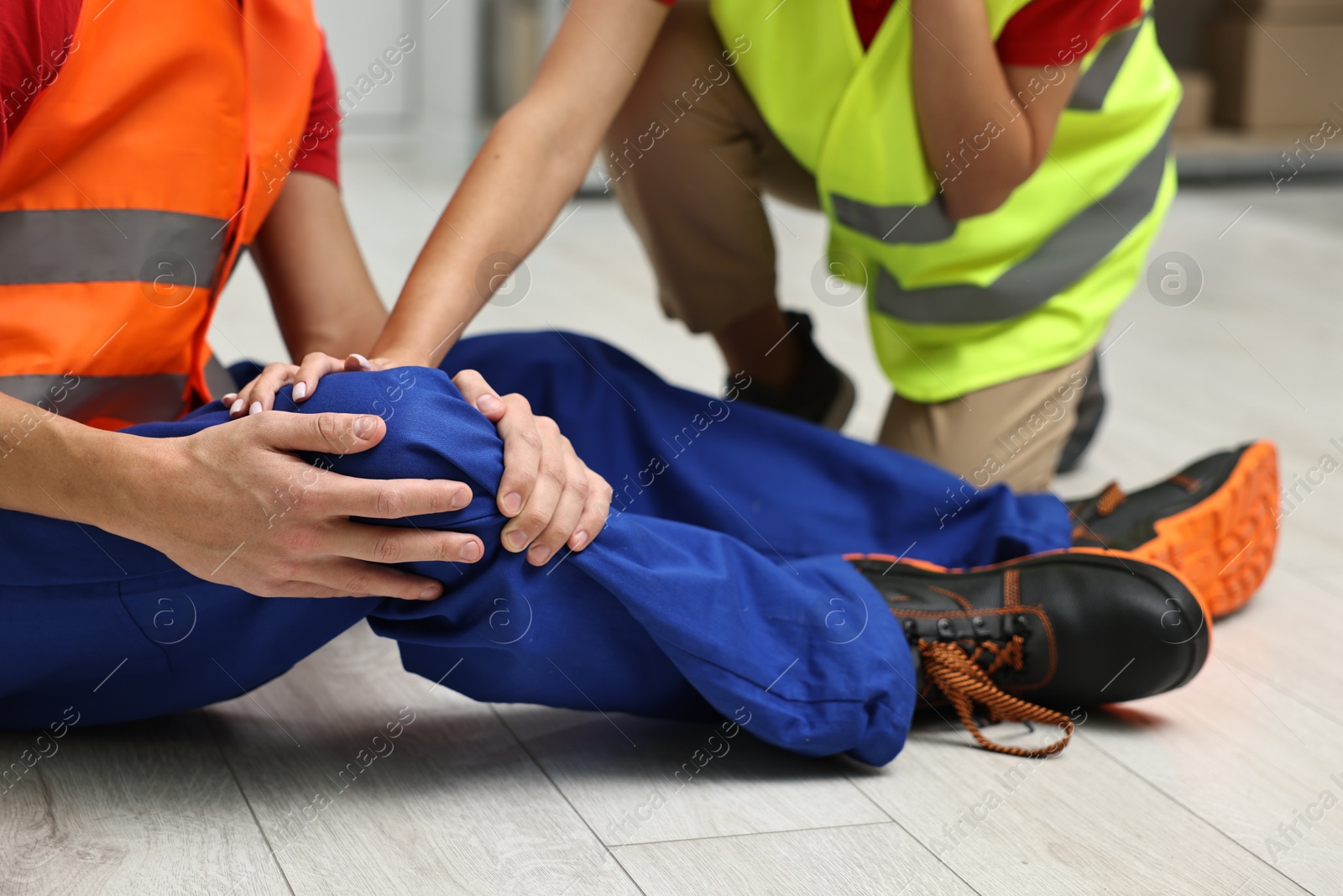 Photo of First aid. Man helping his injured colleague after work accident indoors, closeup