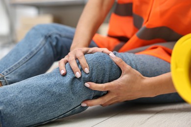 Photo of Accident at work. Woman with injured leg on floor indoors, closeup