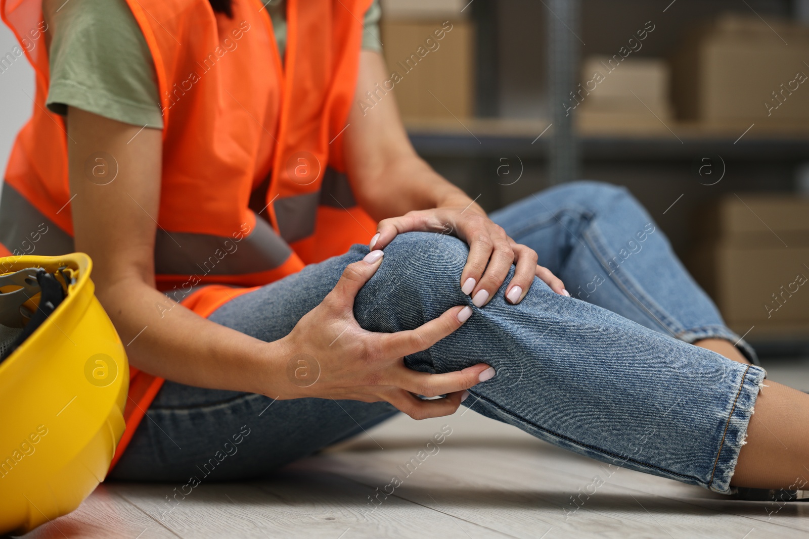 Photo of Accident at work. Woman with injured leg on floor indoors, closeup