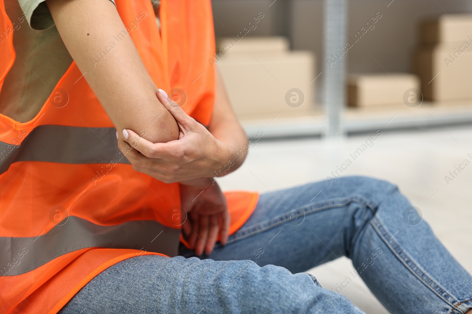 Photo of Accident at work. Woman with injured elbow on floor indoors, closeup