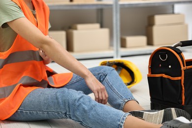 Photo of Accident at work. Woman with injured elbow on floor indoors, closeup