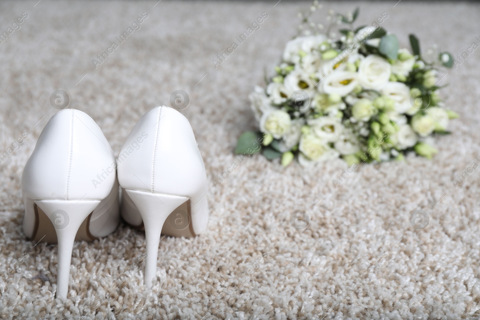 Photo of Wedding. Bridal shoes and bouquet of beautiful flowers on beige carpet, selective focus