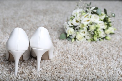 Photo of Wedding. Bridal shoes and bouquet of beautiful flowers on beige carpet, selective focus