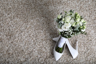 Photo of Wedding bouquet of beautiful flowers and bridal shoes on beige carpet, top view. Space for text