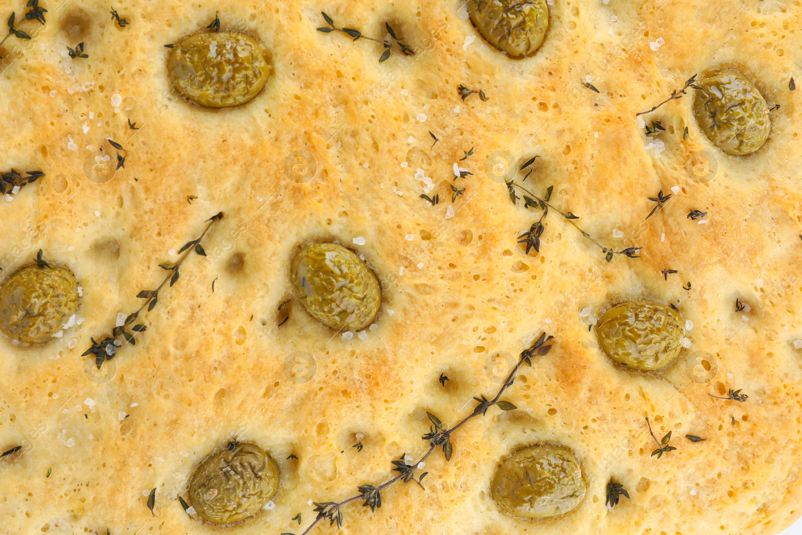 Photo of Delicious focaccia bread with olives, salt and thyme as background, top view