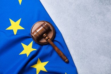 Photo of Judge's gavel and flag of European Union on light grey table, top view. Space for text