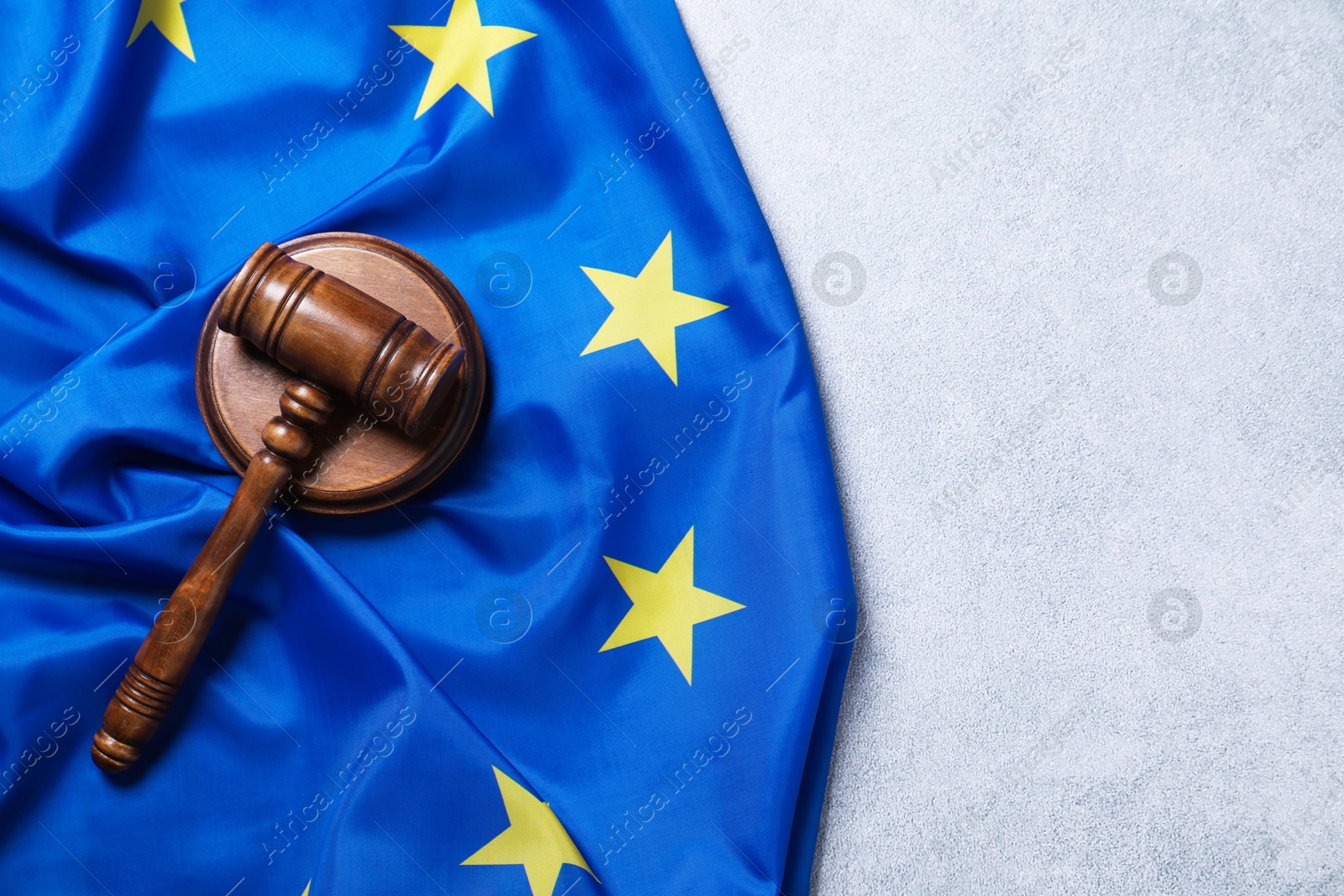 Photo of Judge's gavel and flag of European Union on light grey table, top view. Space for text