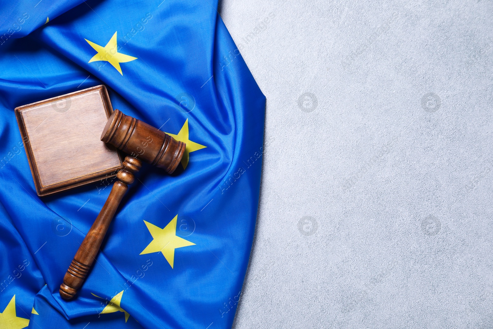 Photo of Judge's gavel and flag of European Union on light grey table, top view. Space for text