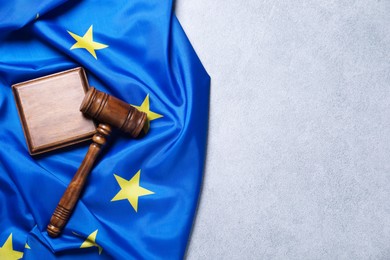 Photo of Judge's gavel and flag of European Union on light grey table, top view. Space for text