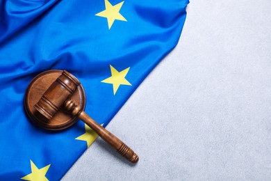 Photo of Judge's gavel and flag of European Union on light grey table, top view. Space for text