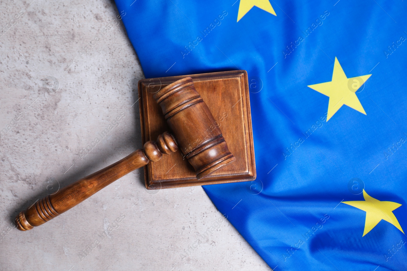 Photo of Judge's gavel and flag of European Union on grey table, top view