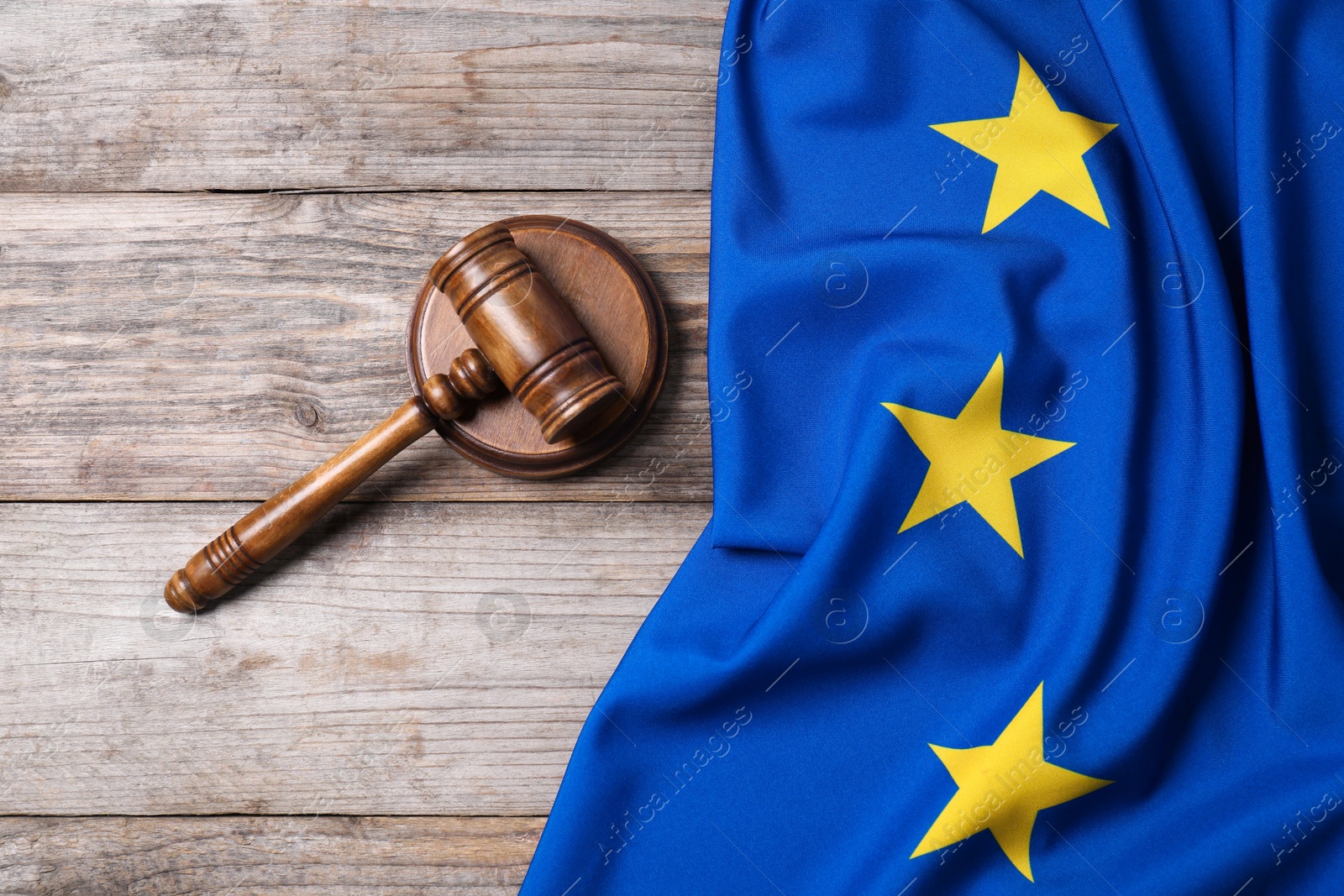 Photo of Judge's gavel and flag of European Union on wooden table, top view