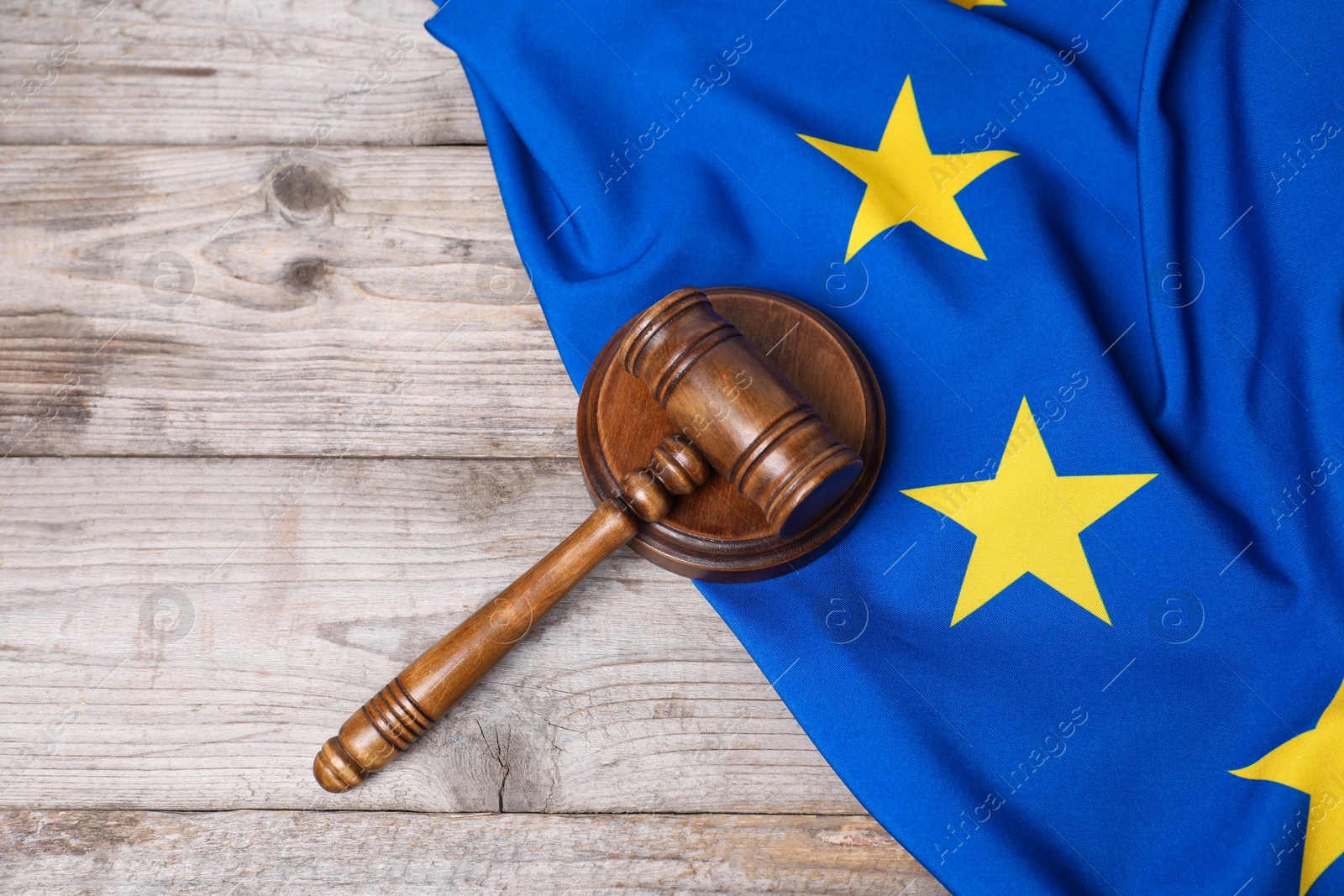 Photo of Judge's gavel and flag of European Union on wooden table, top view. Space for text