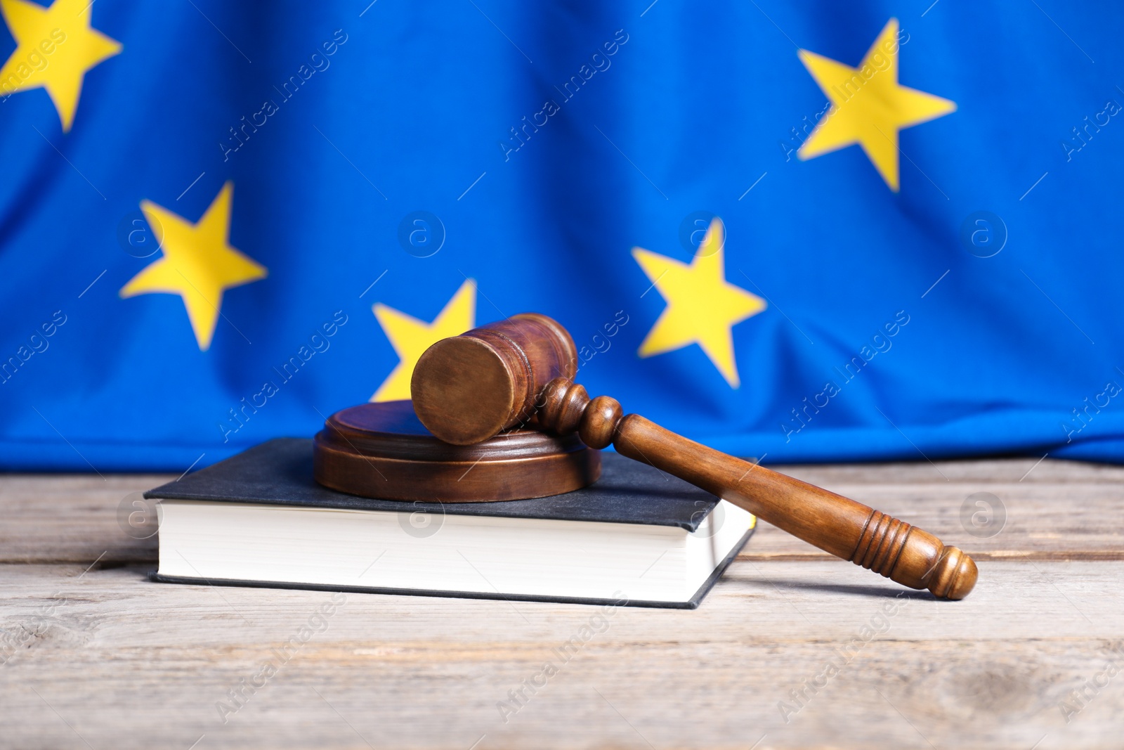 Photo of Judge's gavel and book on wooden table against European Union flag