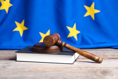 Photo of Judge's gavel and book on wooden table against European Union flag