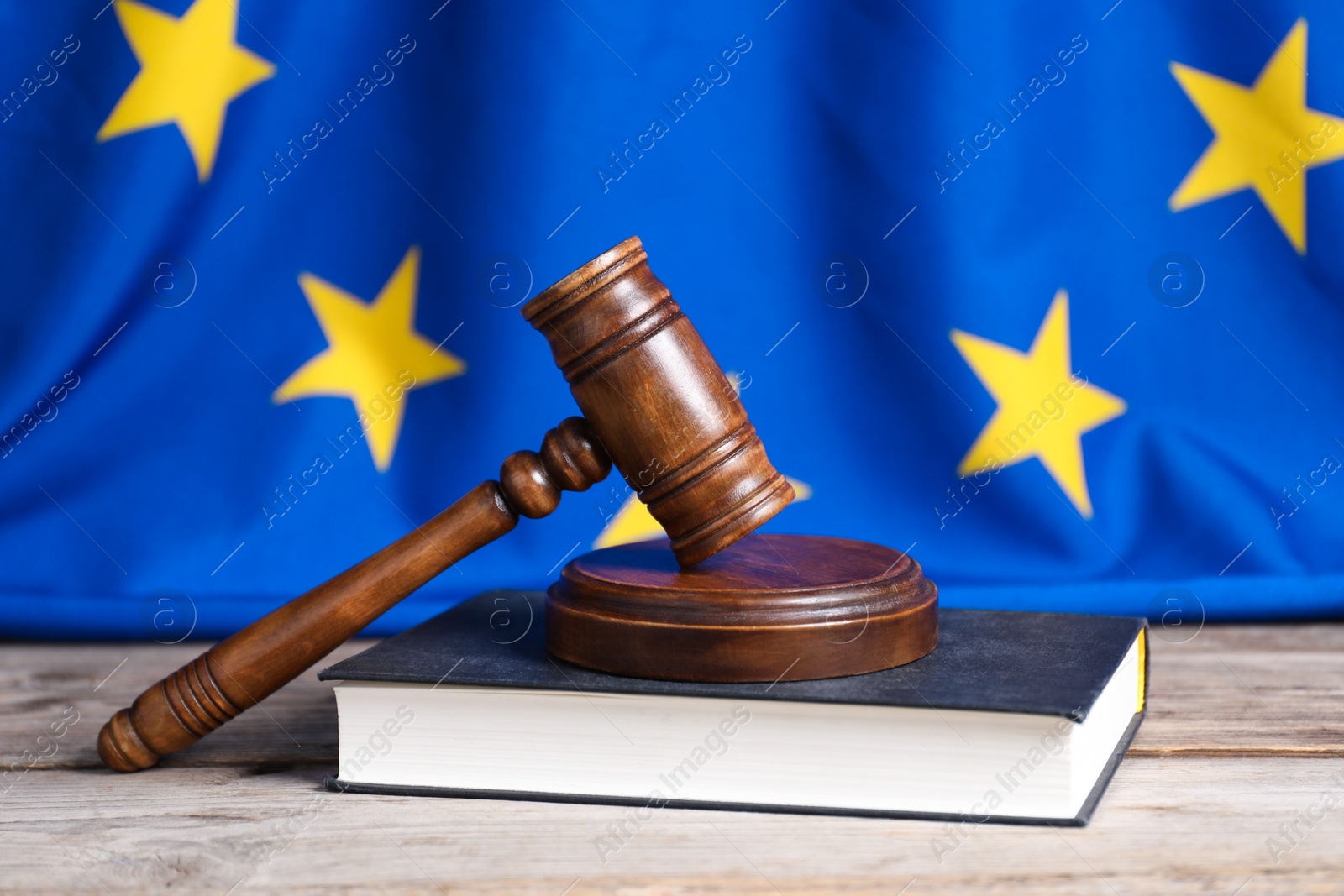 Photo of Judge's gavel and book on wooden table against European Union flag