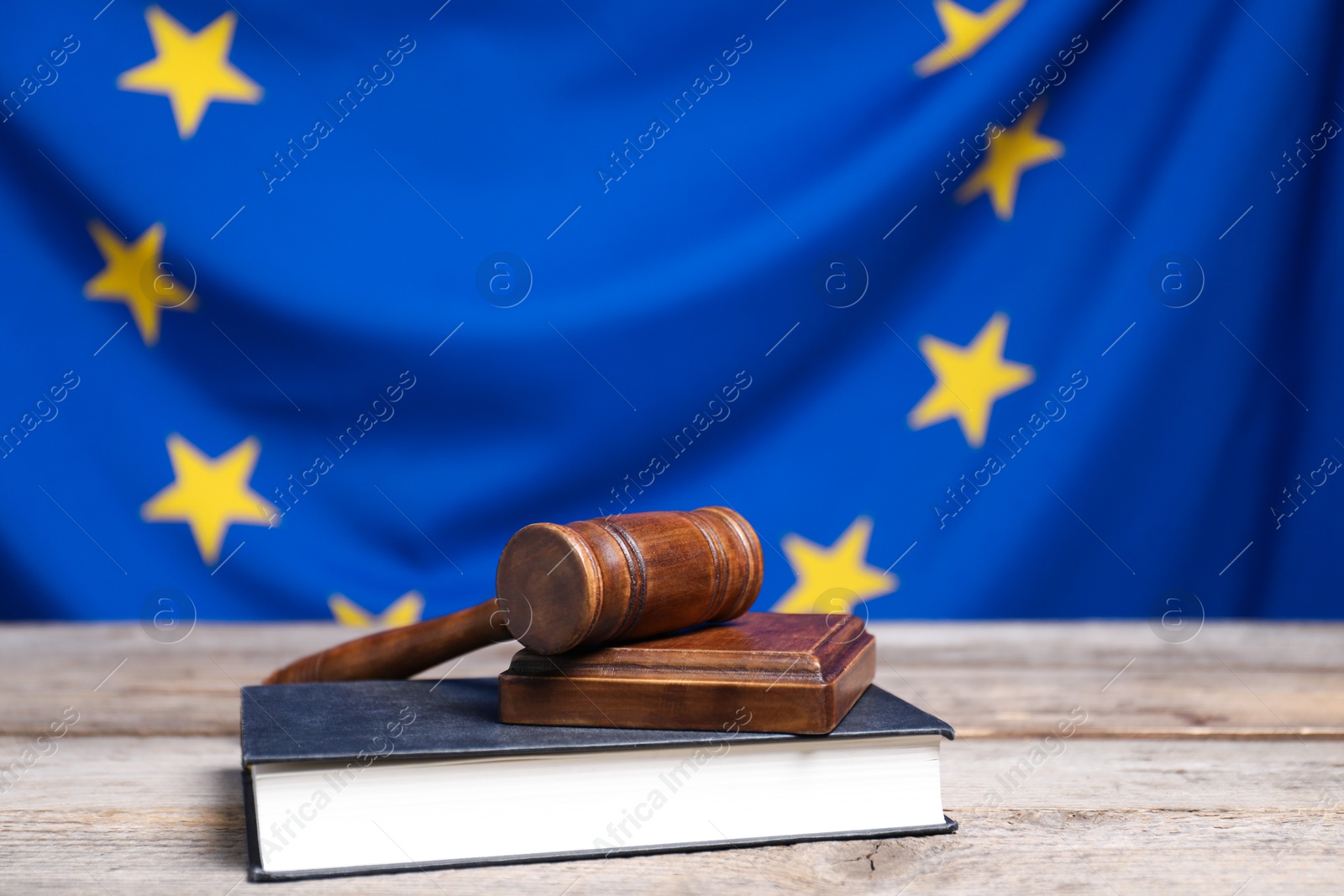 Photo of Judge's gavel on wooden table against European Union flag, closeup